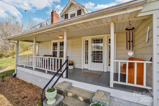 entrance to property featuring covered porch and a chimney