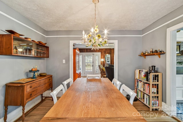 dining space with wood finished floors, a textured ceiling, and a chandelier