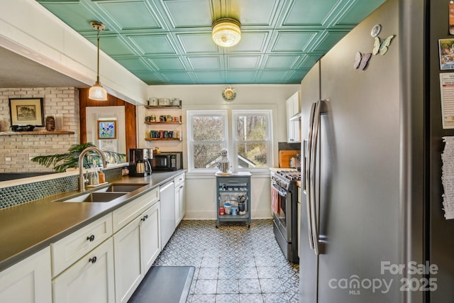 kitchen with dark countertops, appliances with stainless steel finishes, white cabinets, an ornate ceiling, and a sink