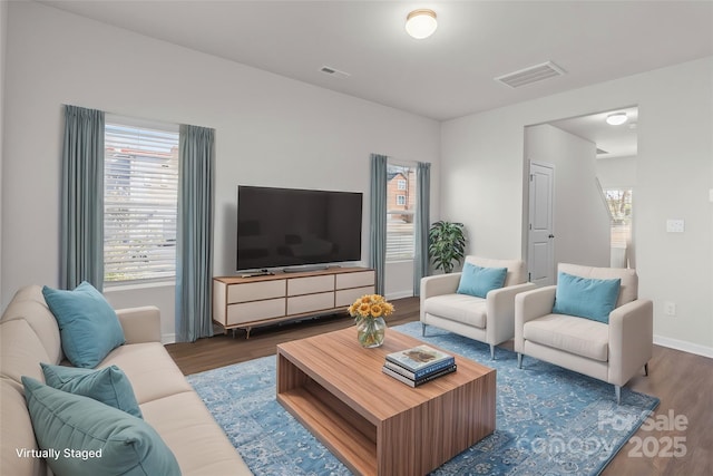 living area with visible vents, baseboards, and wood finished floors