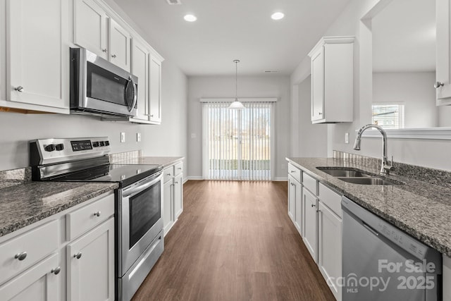 kitchen featuring stainless steel appliances, a sink, white cabinetry, a wealth of natural light, and dark wood finished floors