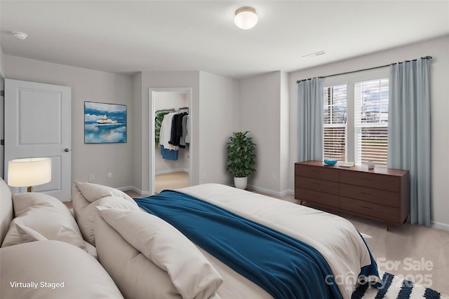 bedroom with a closet, a walk in closet, visible vents, and baseboards