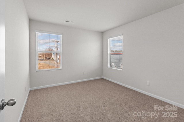 carpeted empty room featuring baseboards and visible vents