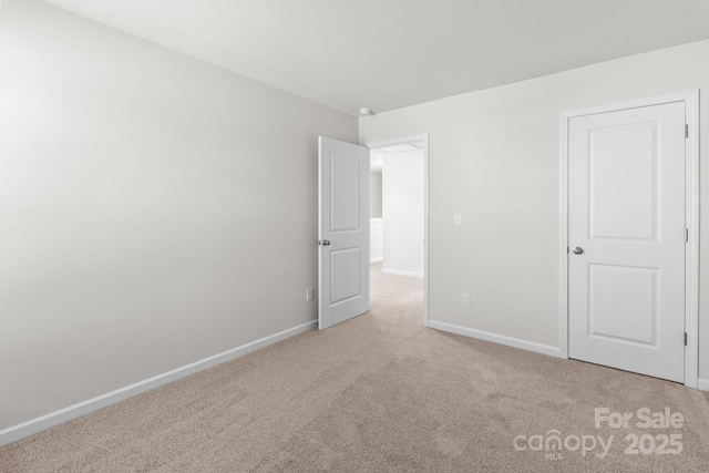 unfurnished bedroom featuring light carpet and baseboards