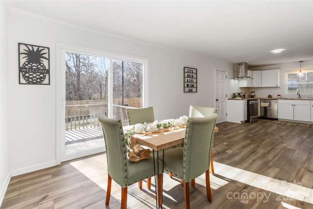 dining space with baseboards, wood finished floors, and crown molding