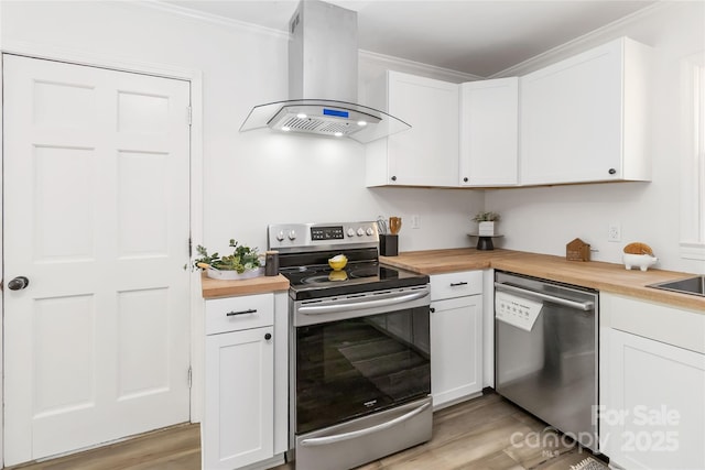 kitchen featuring light wood-style flooring, ornamental molding, range hood, stainless steel appliances, and wooden counters