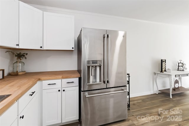 kitchen featuring stainless steel fridge, ornamental molding, wood finished floors, white cabinetry, and wooden counters