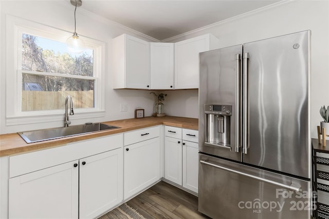 kitchen featuring ornamental molding, high quality fridge, a sink, and butcher block counters