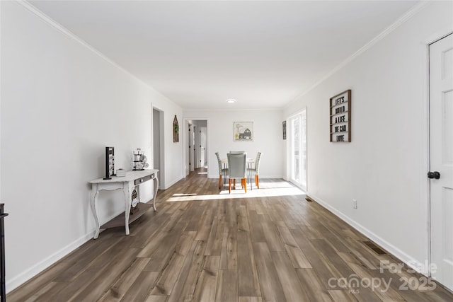 unfurnished dining area featuring crown molding, baseboards, and wood finished floors