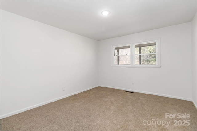 carpeted spare room with visible vents and baseboards