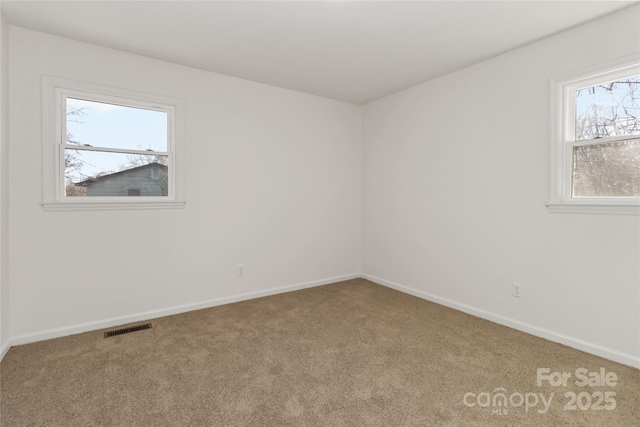 carpeted spare room with baseboards and visible vents