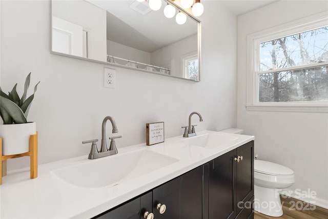 full bath featuring double vanity, a sink, and toilet