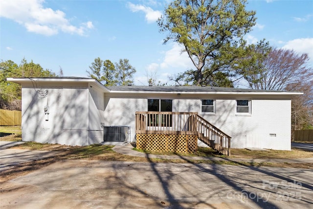 rear view of property featuring crawl space, fence, cooling unit, a wooden deck, and brick siding