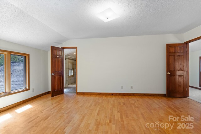 15 Elmwood Ln Unit 161, Asheville, NC 28803 - spare room featuring light wood-type flooring, a textured ceiling, baseboards, and lofted ceiling
