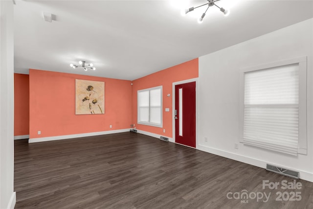 unfurnished living room with visible vents, baseboards, and dark wood finished floors