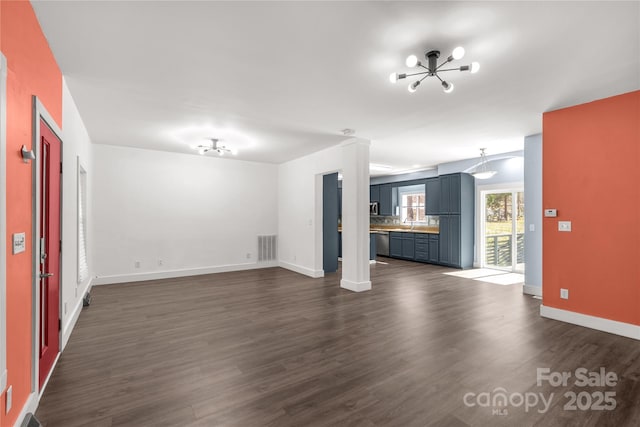 unfurnished living room with dark wood-type flooring, baseboards, visible vents, and a chandelier