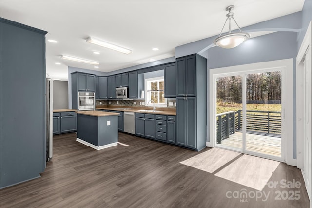 kitchen featuring pendant lighting, a sink, dark wood finished floors, appliances with stainless steel finishes, and light countertops