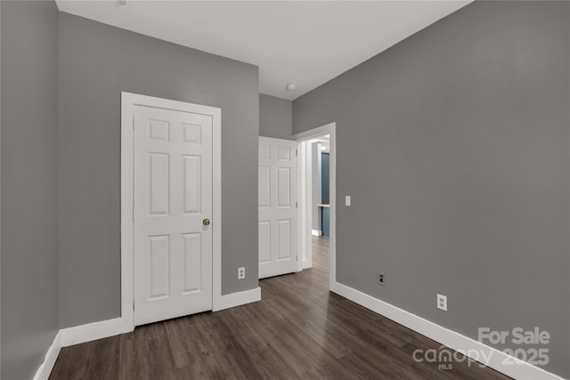 unfurnished bedroom featuring dark wood-type flooring and baseboards