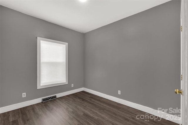 spare room featuring visible vents, baseboards, and dark wood-style flooring