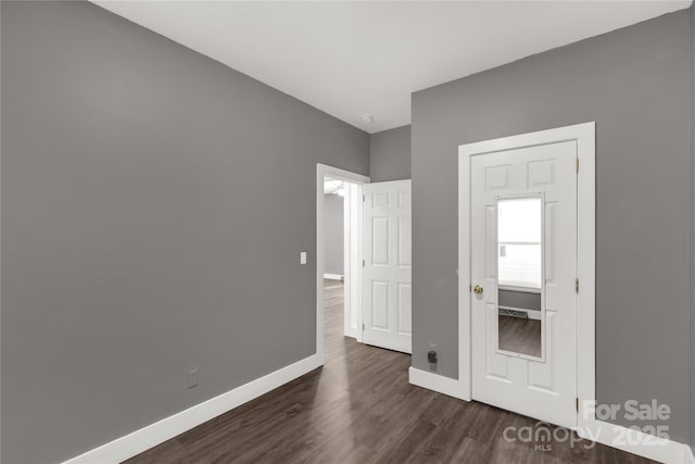 unfurnished bedroom featuring dark wood-type flooring and baseboards