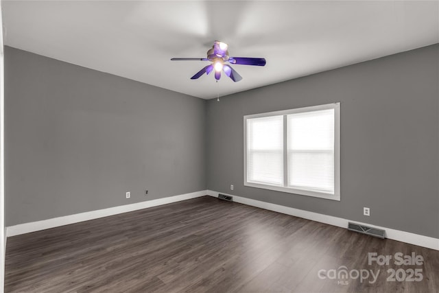 spare room featuring dark wood-type flooring, baseboards, and visible vents