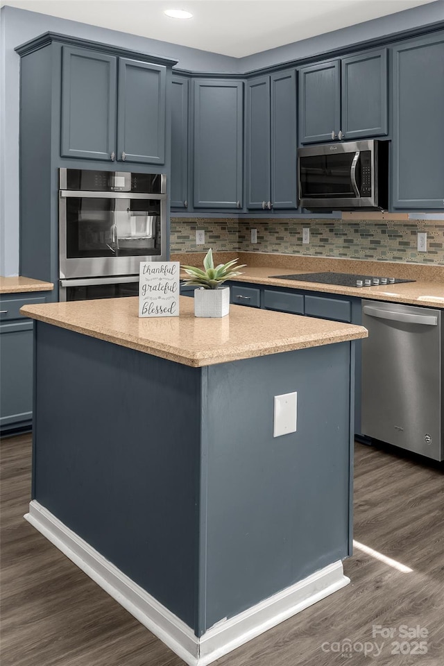 kitchen featuring light stone counters, dark wood-style floors, a center island, appliances with stainless steel finishes, and decorative backsplash