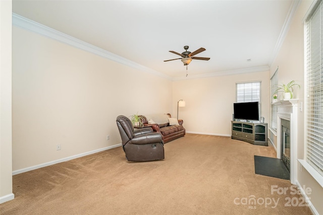 living area featuring a fireplace with flush hearth, a ceiling fan, carpet floors, crown molding, and baseboards