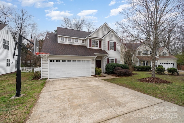 traditional-style home featuring driveway, a front lawn, fence, an attached garage, and a shingled roof