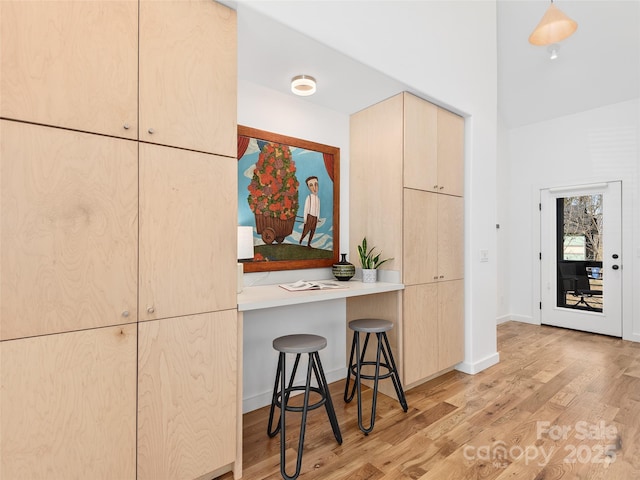 433 W Haywood St, Asheville, NC 28801 - kitchen with light brown cabinets, baseboards, a kitchen bar, and light wood-style floors