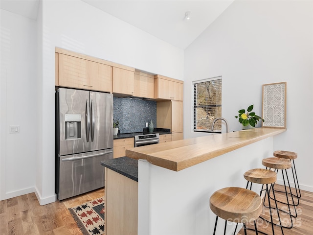 433 W Haywood St, Asheville, NC 28801 - kitchen featuring light brown cabinets, oven, a kitchen bar, backsplash, and stainless steel refrigerator with ice dispenser