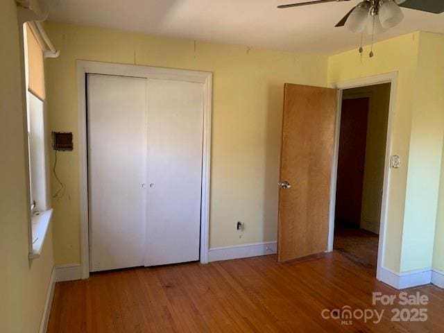 unfurnished bedroom with a closet, baseboards, and wood finished floors