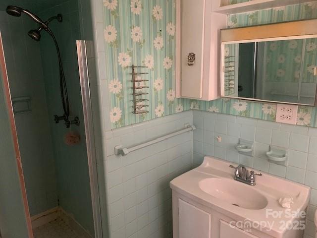 bathroom featuring a wainscoted wall, a shower stall, vanity, and wallpapered walls