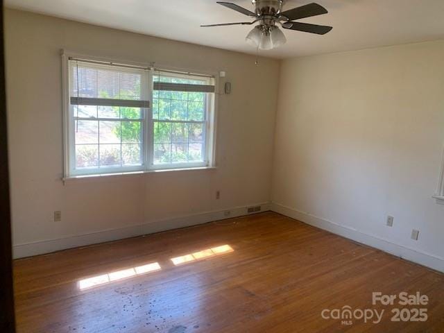 empty room with ceiling fan, baseboards, and wood finished floors