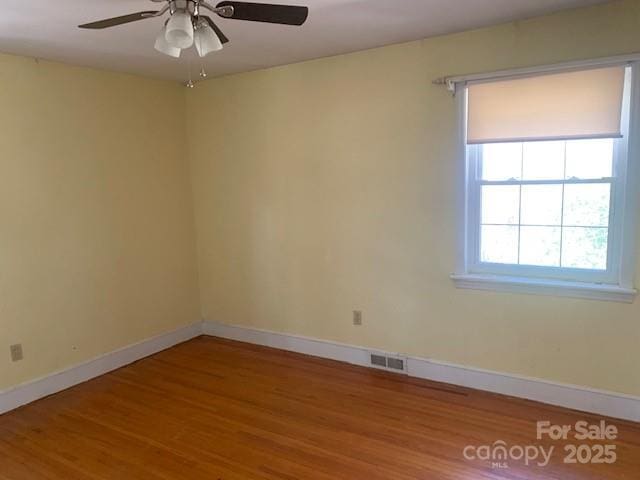 unfurnished room featuring visible vents, ceiling fan, baseboards, and wood finished floors