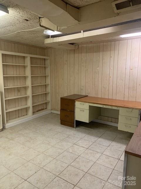 unfurnished office featuring visible vents and wooden walls