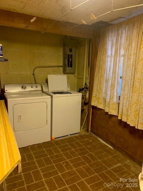 laundry room with washing machine and dryer, laundry area, electric panel, and concrete block wall