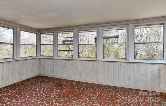 unfurnished sunroom with a wealth of natural light, tile patterned floors, and baseboards