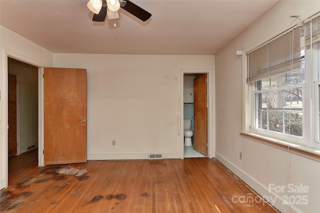 unfurnished bedroom featuring visible vents, baseboards, connected bathroom, and hardwood / wood-style flooring