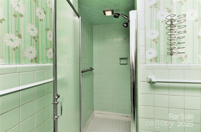 full bath with a wainscoted wall, tile walls, and a stall shower