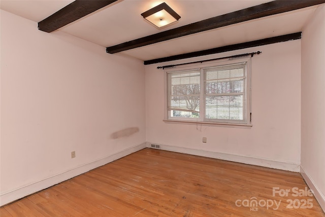 empty room with beamed ceiling, baseboards, light wood-style floors, and visible vents