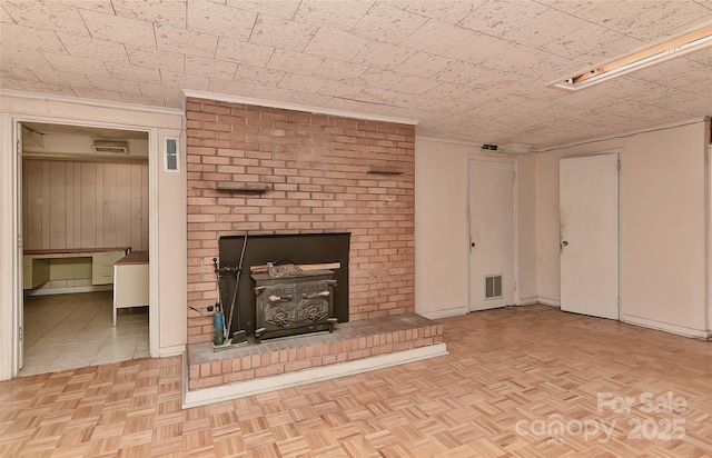 unfurnished living room featuring visible vents, wood walls, and parquet floors