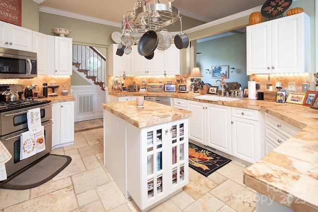 kitchen featuring stone tile floors, ornamental molding, stainless steel appliances, and decorative backsplash