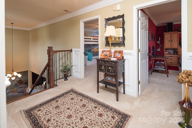 hall with a notable chandelier, visible vents, an upstairs landing, carpet, and crown molding