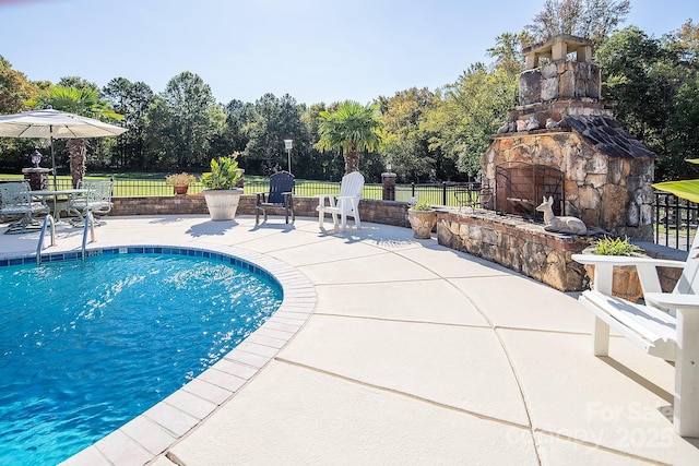 view of pool featuring a patio, an outdoor stone fireplace, and fence