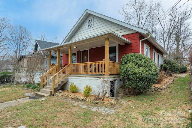 view of front of house featuring covered porch, fence, and a front yard