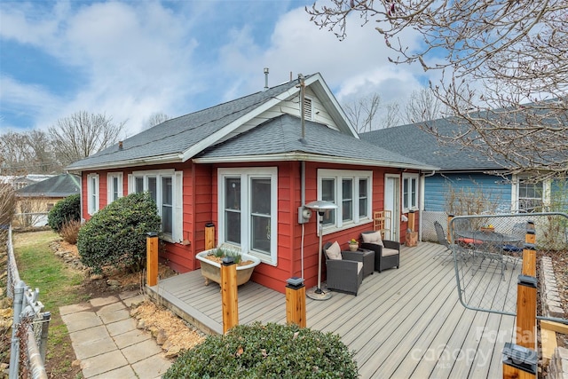 rear view of property featuring a shingled roof and a wooden deck