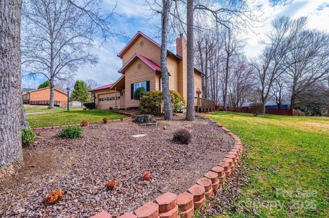 view of home's exterior with a deck, fence, a yard, a garage, and a chimney