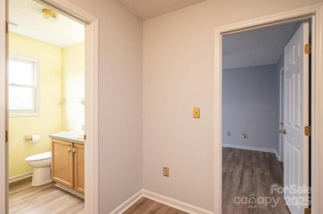 bathroom with wood finished floors, vanity, and baseboards