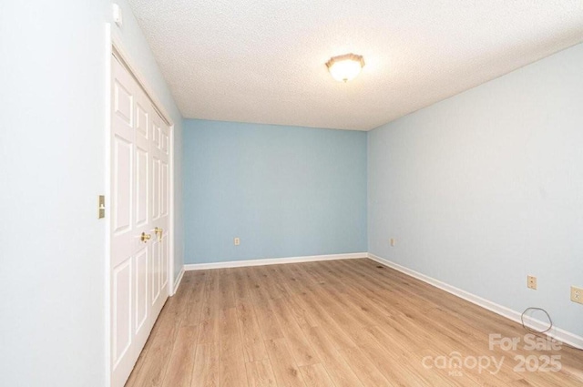 unfurnished room featuring light wood-style flooring, baseboards, and a textured ceiling