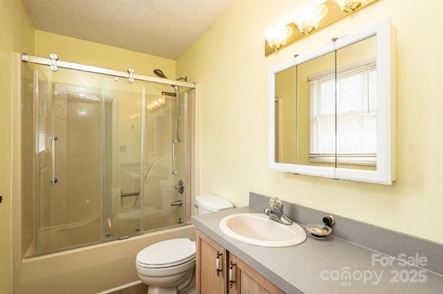 bathroom featuring a textured ceiling, shower / bath combination with glass door, vanity, and toilet